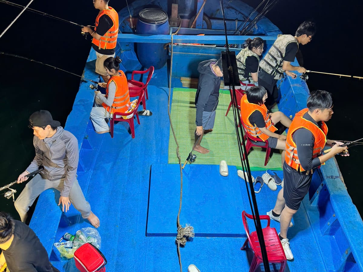 Guests squid fishing along the rail under the boat floodlights at night off Da Nang